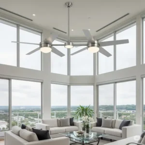 A contemporary dual ceiling fan in a brushed nickel finish with integrated lights, hanging from a high ceiling in a modern living room with panoramic windows.