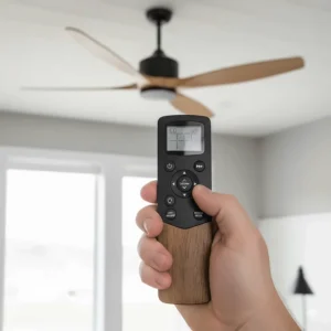 Hand holding a remote control used to adjust the speed and light settings of a multi-speed farmhouse ceiling fan.