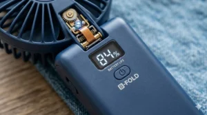 Close-up of a modern foldable handheld fan showing a digital display of its long-lasting battery life.