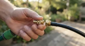 Close-up of a person installing a low pressure misting kit nozzle onto a garden hose connector.