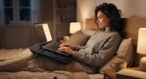 A person relaxing comfortably with a laptop cooling pad for bed during a late-night work session.